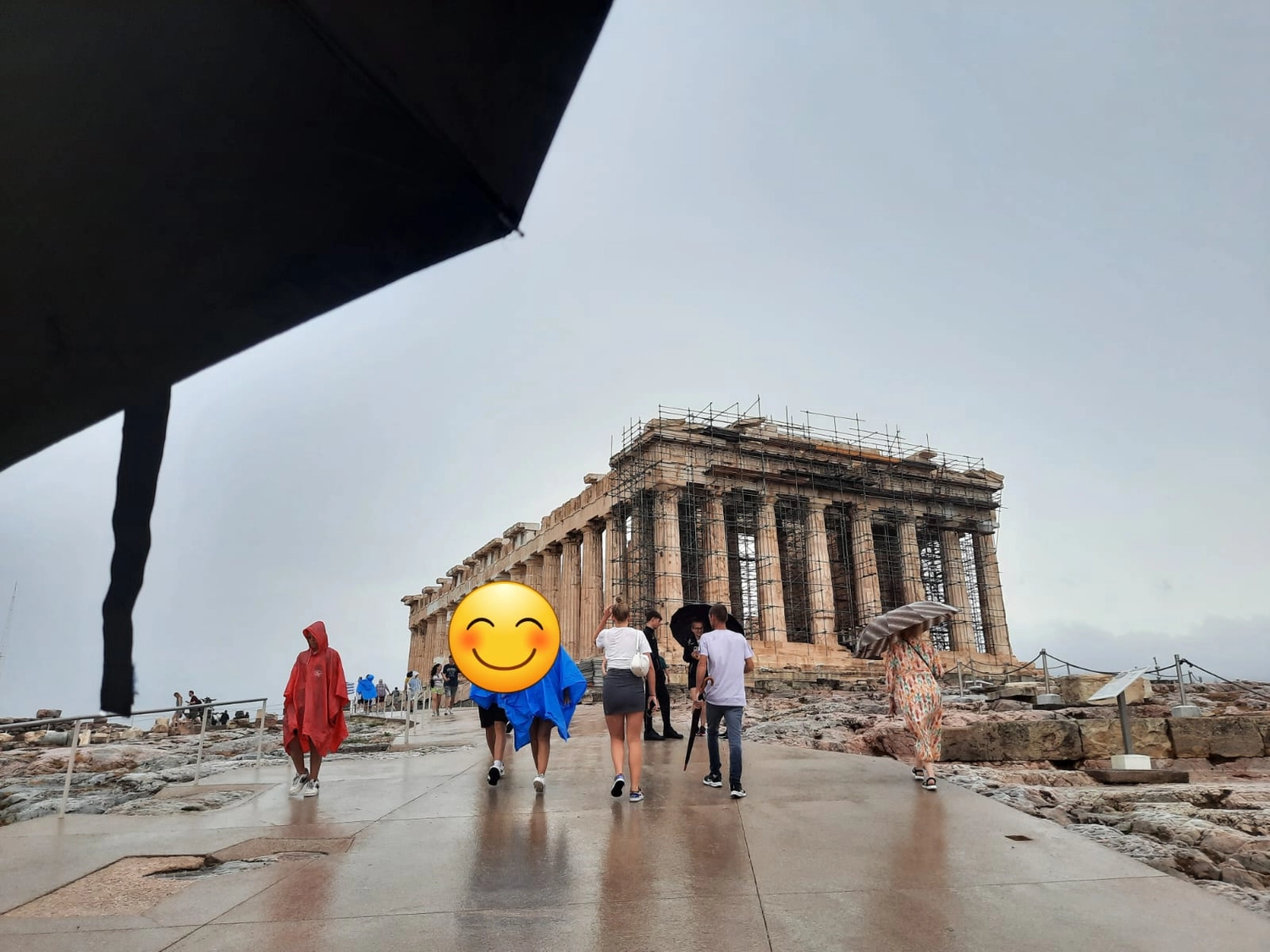 Mbaye Jeng – Companionship Service - Dieses Bild zeigt Besucher, die an einem regnerischen Tag am Parthenon navigieren, einem ikonischen antiken Tempel auf der Akropolis von Athen in Griechenland.