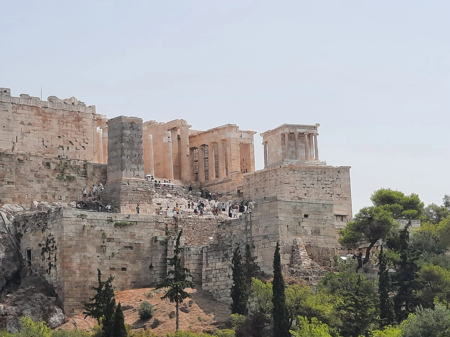 Mbaye Jeng – Companionship Service -Dieses Bild zeigt die Akropolis von Athen, insbesondere die Propyläen (das monumentale Tor) und den Tempel der Athene Nike auf der rechten Seite.